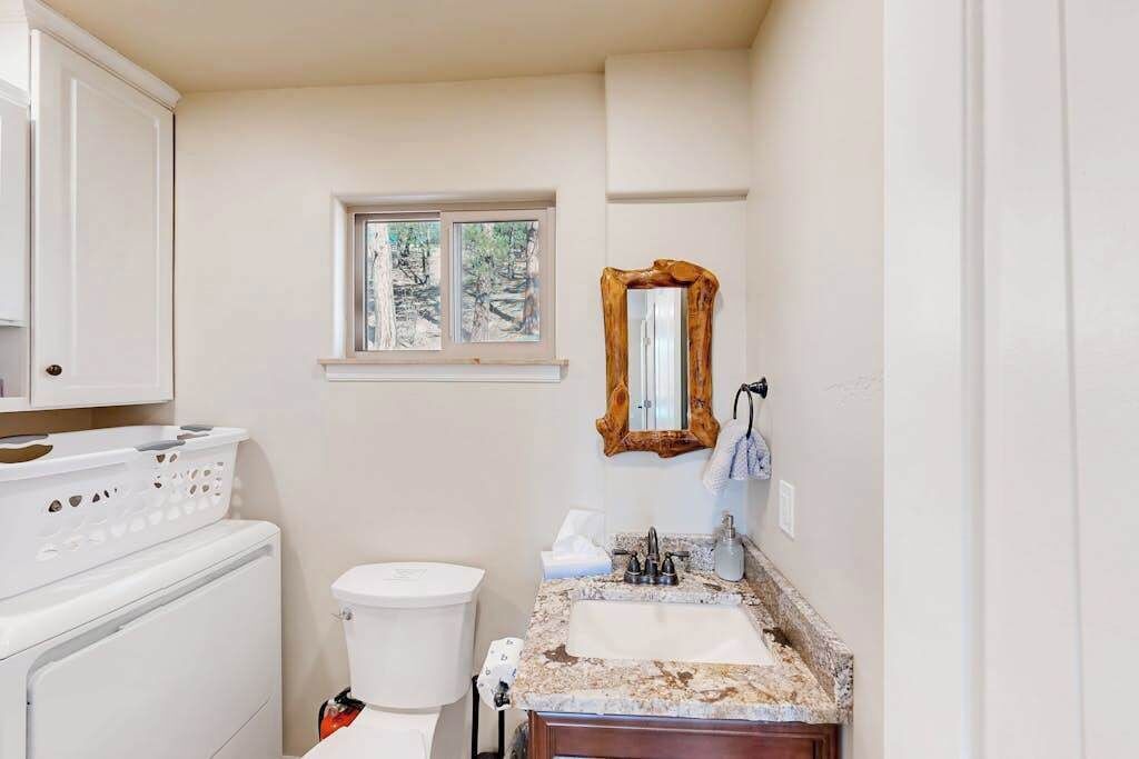 A compact bathroom with a toilet, sink, and a window above the sink.
