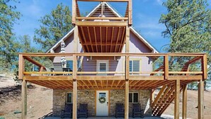A multi-level wooden structure with a central staircase, a door with a wreath, and two benches outside. - Five Mile Retreat- Spacious Retreat • Large Deck & WiFi (Cripple Creek)