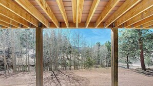 A covered outdoor area with a view of a forested landscape. - Five Mile Retreat- Spacious Retreat • Large Deck & WiFi (Cripple Creek)