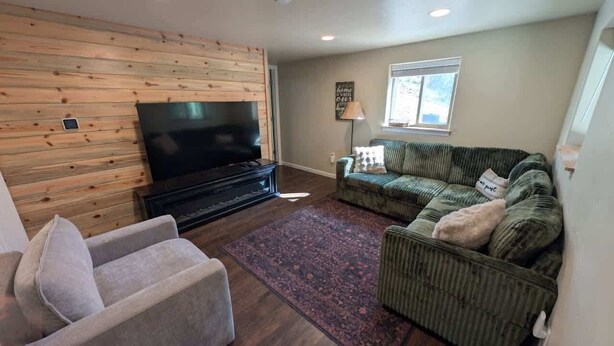 A living room with a flat-screen TV, a sofa, a chair, and a patterned rug. - Five Mile Retreat- Spacious Retreat • Large Deck & WiFi (Cripple Creek)