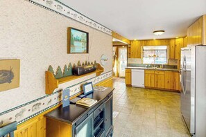 A kitchen with wooden cabinets, a refrigerator, and a window. - Rainbows End - Mountain-View Home • Basketball Court (Cripple Creek)