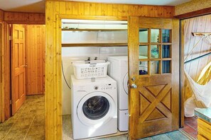 A laundry room with wooden walls, a washing machine, a dryer, and a door with a window. - Rainbows End - Mountain-View Home • Basketball Court (Cripple Creek)