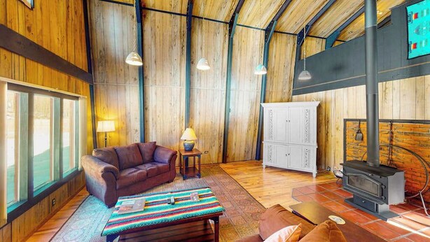 Um interior em madeira com um sofá, uma mesa, um armário e uma lareira.