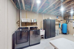 A laundry room with a washing machine, dryer, and a large water tank. - Bear Butte Retreat - Private Hot Tub Retreat • Secluded (Deadwood)