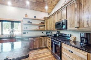 Une cuisine avec des meubles en bois, une cuisinière, un four à micro-ondes et une machine à café.