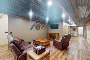 Ein geräumiges Wohnzimmer mit Kamin, Ledersofas, einem Holztisch und einem Schachbrett.