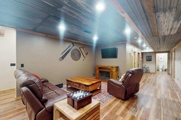 Ein geräumiges Wohnzimmer mit Kamin, Ledersofas, einem Holztisch und einem Schachbrett.