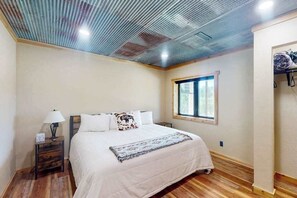 Ein Schlafzimmer mit einem Bett, einem Nachttisch, einem Fenster und Holzboden.