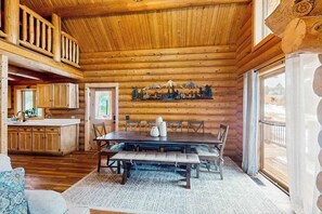 Ein rustikales Blockhaus-Interieur mit Essbereich, Küche und schöner Aussicht durch das Fenster.
