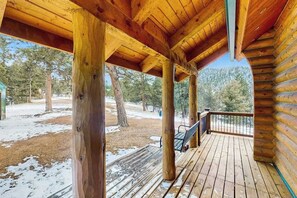 Eine Holzterrasse mit einer Bank, umgeben von Bäumen und blauem Himmel.