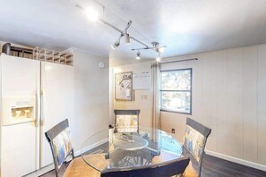 A dining area with a glass table and chairs, a white refrigerator, and a window with a view. - Dog-Friendly Rustic Cabin w/ Fireplace (Florissant)