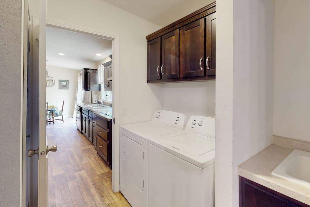 A laundry area with a washing machine and dryer, a sink, and wooden cabinets.