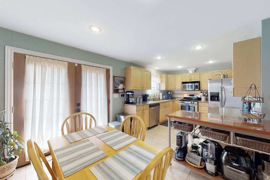 A compact kitchen with modern appliances, a dining area with a table and chairs, and a sliding glass door leading to a balcony.