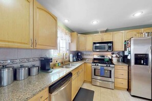 Eine Küche mit Holzausstattung, Edelstahlgeräten, einer Mikrowelle, einer Kaffeemaschine und einem Kühlschrank.