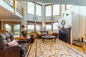 A spacious living room with a fireplace, large windows, and a high ceiling. - Skyline Ridge - Secluded Retreat • Stunning Views & Loft (Florissant)