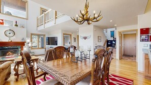 A spacious dining area with a wooden table and chairs, a chandelier, and a fireplace. - Skyline Ridge - Secluded Retreat • Stunning Views & Loft (Florissant)