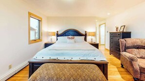 A bedroom with a large bed, bedside tables, a dresser, and a patterned bench. - Skyline Ridge - Secluded Retreat • Stunning Views & Loft (Florissant)