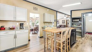 A modern kitchen with a dining area, wooden cabinets, and a stainless steel refrigerator. - Rocky Mountain Rustic - Mountain-View Home • AC & Fast WiFi (Colorado Springs)