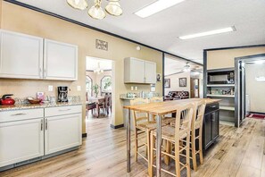 A modern kitchen with a dining area, wooden cabinets, and a stainless steel refrigerator. - Rocky Mountain Rustic - Mountain-View Home • AC & Fast WiFi (Colorado Springs)