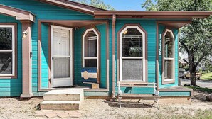 A single-story house with a front porch, a door, and two windows. - Rocky Mountain Rustic - Mountain-View Home • AC & Fast WiFi (Colorado Springs)