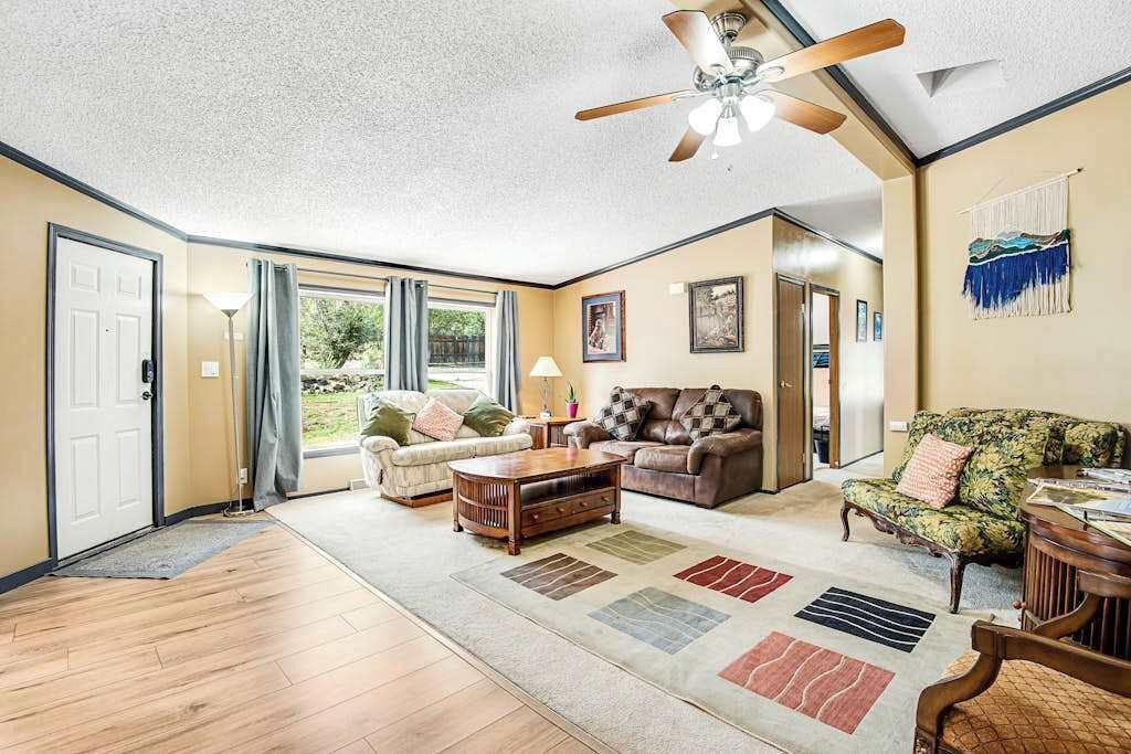Un salon spacieux doté d’un ventilateur de plafond, d’une table basse en bois et d’un tapis à motifs.