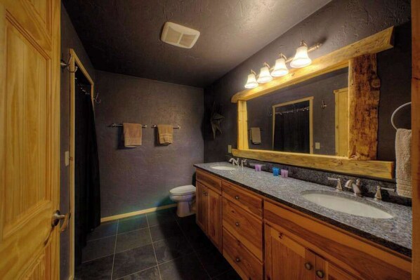 Ein Badezimmer mit einem Holztisch, zwei Waschbecken, einem großen Spiegel und einer Toilette.