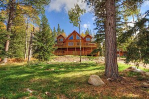 A lodge with a wooden exterior, multiple levels, and a deck area surrounded by trees. - Black Diamond Lodge - Log Lodge • Hot Tub & Game Room (Lead)