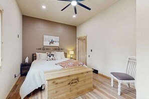 Ein Schlafzimmer mit Bett, Nachttisch, Lampe und einem Sessel.