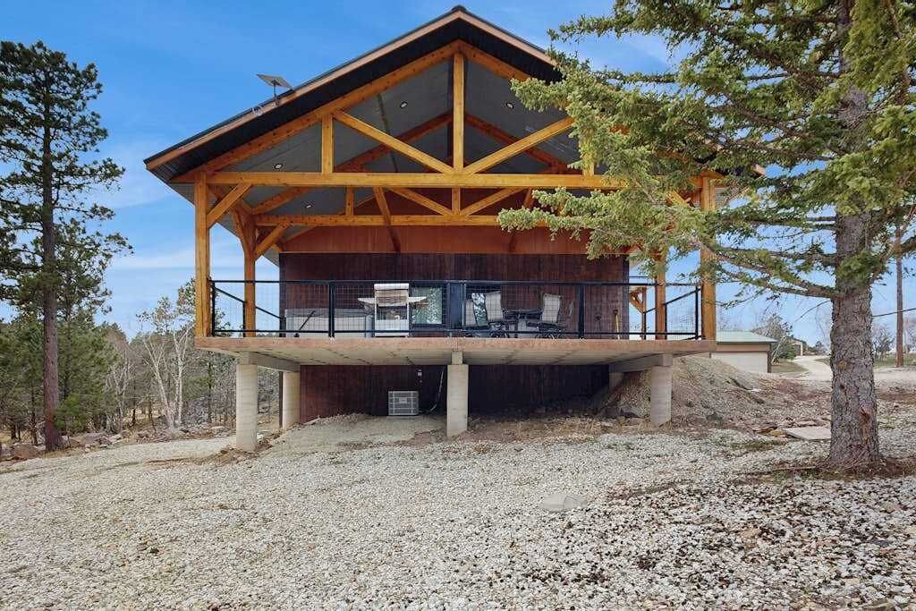 Une cabane en bois à deux étages, dotée d’un balcon et entourée d’arbres.