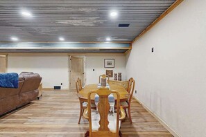 A dining area with a wooden table and chairs, a brown leather couch, and a ceiling with visible insulation and recessed lighting. - Bear Butte Hideaway - Secluded Hideaway w/ Private Hot Tub (Deadwood)