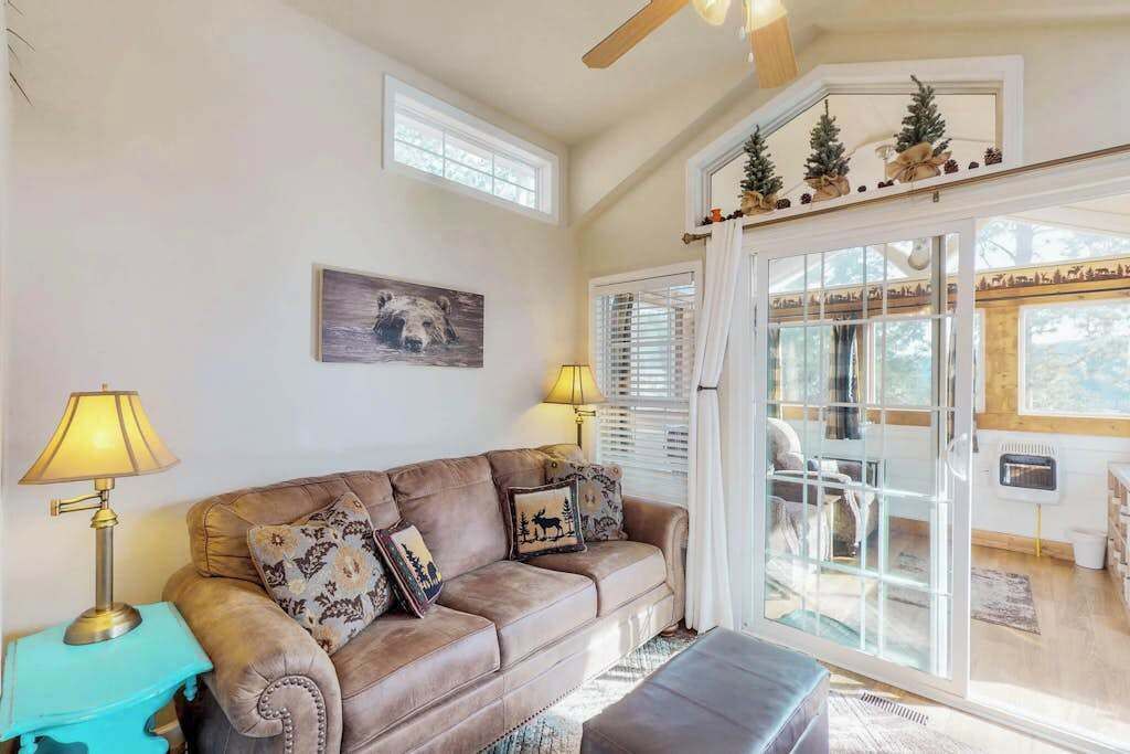 A living room with a brown leather sofa, two lamps, a framed picture, and a sliding glass door leading to a balcony.