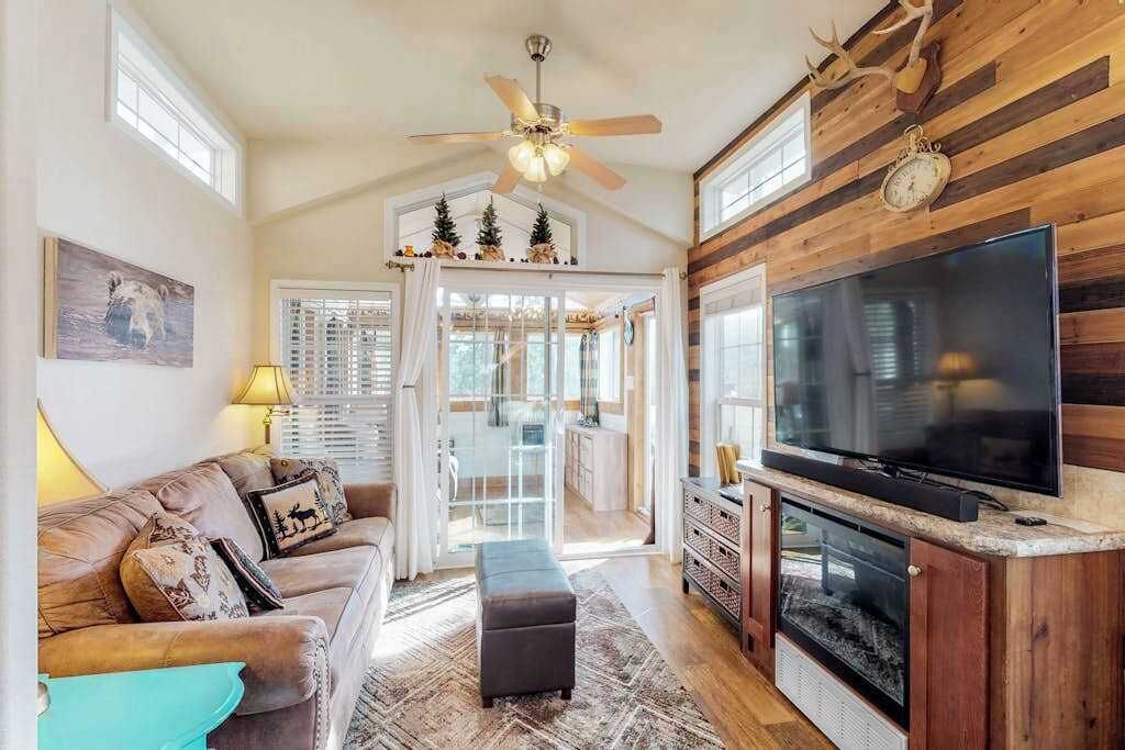 Un salon confortable avec une cheminée, un téléviseur et un ventilateur de plafond.