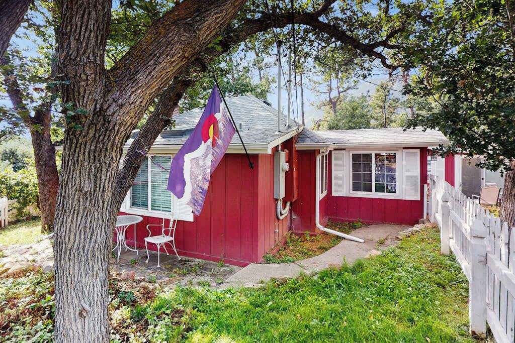 A red building with a white fence, a flag, and a small patio with chairs.