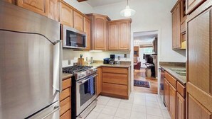 Une cuisine avec des meubles en bois, des appareils électroménagers en acier inoxydable et un luminaire suspendu.