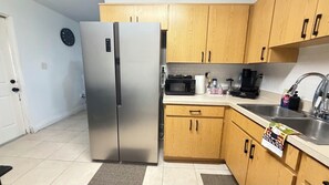 A kitchen with wooden cabinets, a stainless steel refrigerator, a microwave, a coffee maker, and a sink. - Relaxing Melbourne Home Away from Home (Melbourne)