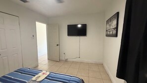 A bedroom with a bed, a television mounted on the wall, and a door leading to another room. - Relaxing Melbourne Home Away from Home (Melbourne)