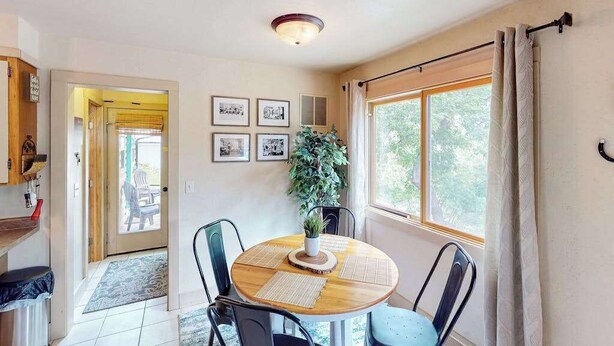 A dining area with a round table, chairs, a potted plant, and framed pictures on the wall. - Mountain View Escape - Dog-Friendly Cabin • Amazing Views (Lead)