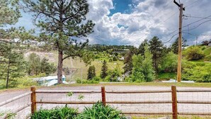 A fenced area with a view of a rural landscape, including trees and a distant village. - Mountain View Escape - Dog-Friendly Cabin • Amazing Views (Lead)