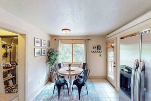 A dining area with a round table, chairs, a potted plant, and a refrigerator. - Mountain View Escape - Dog-Friendly Cabin • Amazing Views (Lead)