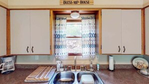 A kitchen with a double sink, cabinets, a coffee maker, and a sign above the window that reads 'Bless This House.' - Mountain View Escape - Dog-Friendly Cabin • Amazing Views (Lead)