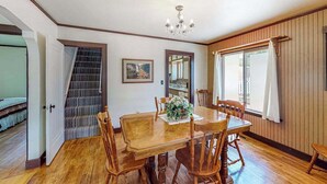 A dining area with a wooden table and chairs, a chandelier, and a staircase leading to another room. - Miners Cottage - Cozy Cottage • Fireplace Near Deadwood (Lead)