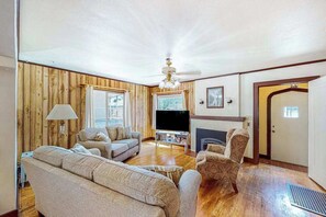 Ein Wohnzimmer mit Kamin, Holzwänden, Fernseher und einer Couch.