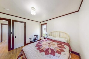 Ein Schlafzimmer mit Bett, Stuhl, Schreibtisch und Tür.