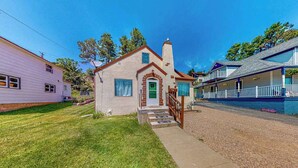 A single-story house with a front porch and a green door. - Miners Cottage - Cozy Cottage • Fireplace Near Deadwood (Lead)