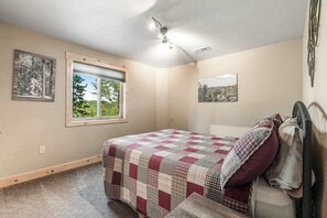 A bedroom with a bed, a window, a ceiling fan, and two wall-mounted artworks. - Klassy Lodge - Private Hot Tub & Game Room (Sturgis)