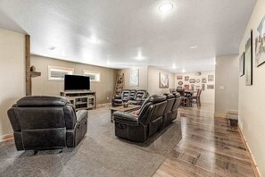A spacious living room with a large sectional sofa, a recliner, and a flat-screen TV. - Klassy Lodge - New Lodge • Private Hot Tub & Game Room (Sturgis)
