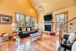 Ein geräumiges Wohnzimmer mit Kamin, Ledersofas und einem großen Fernseher.