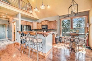 A spacious kitchen with a central island, bar stools, and a dining table.