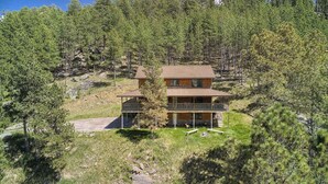 En toetagers hytte med balkon, omgivet af skov.