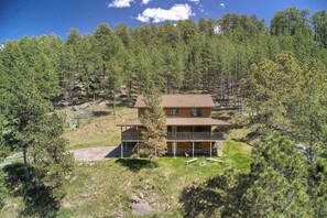 A two-story cabin with a balcony, surrounded by a forested area. - Eagle Pine Lodge - Dog-Friendly Home w/ Pool Access (Custer)